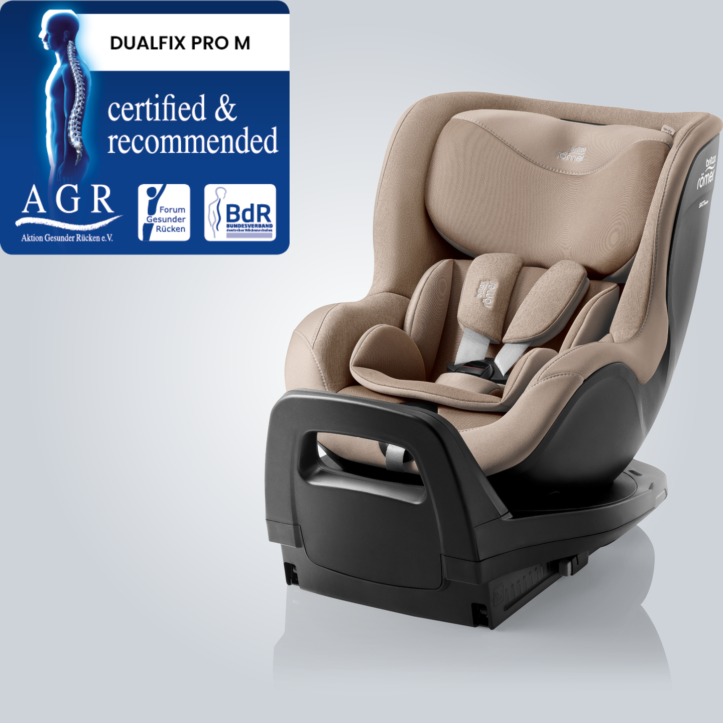 DUALFIX PRO M em Teak, assento automotivo girat&oacute;rio 360&deg; para crian&ccedil;as pequenas com apoio de cabe&ccedil;a ajust&aacute;vel e sistema de cinto, mostrado em vista frontal inclinada com o selo &ldquo;Tested & Recommended&rdquo; da Aktion Gesunder R&uuml;cken e.V.